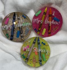 three magnets with crayons and writing on them sitting on a white blanket