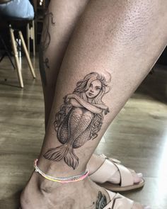 a woman's leg with a mermaid tattoo on it