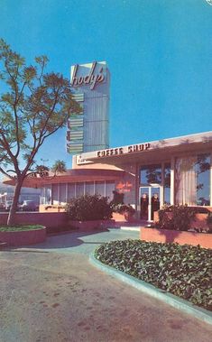 an old photo of a hotel with trees and bushes in front of it on a sunny day