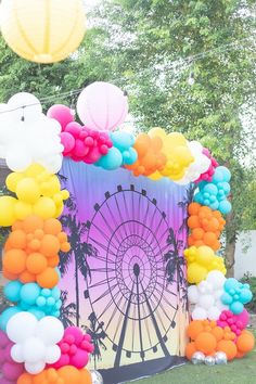 an arch decorated with balloons and other decorations in the shape of a ferris wheel is shown