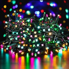 multicolored christmas lights are on the floor in front of a black background with blurry lights