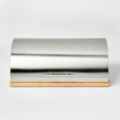 a metal box with a wooden handle on it's side, sitting on a white surface