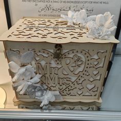 a decorative box is on display in a glass case with flowers and ribbons around it