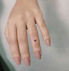 a woman's hand with a tiny heart tattoo on her left thumb and finger