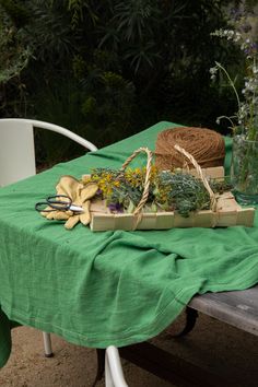 a green table cloth with flowers and gardening utensils sitting on top of it