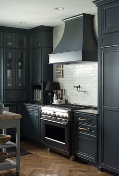 a kitchen with dark blue cabinets and stainless steel stove top oven, wood flooring