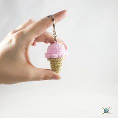 a hand holding a tiny crocheted ice cream cone keychain on a chain