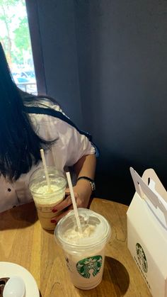 a woman sitting at a table with a starbucks drink