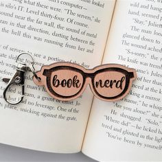 the book nerd keychain is made out of wood and has glasses on it