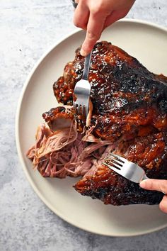 someone is cutting into a large piece of meat on a plate with a fork and knife