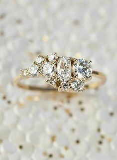 three stone diamond ring sitting on top of white speckled paper with gold flecks