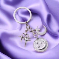 a keychain with two crosses and a crescent on it sitting on a purple fabric