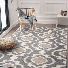 a gray and white area rug with a wooden chair in front of a large window