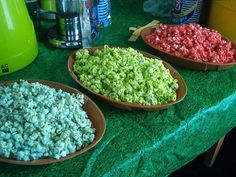 three bowls filled with popcorn sitting on top of a green table