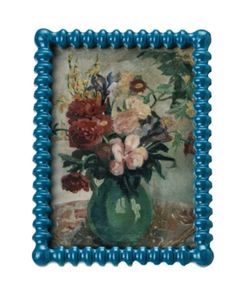 a green vase with flowers in it on a white background and blue beaded frame