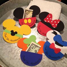 several mickey mouse magnets are on a tray with a dollar bill in the middle