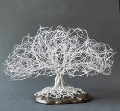 a white wire tree sculpture sitting on top of a rock