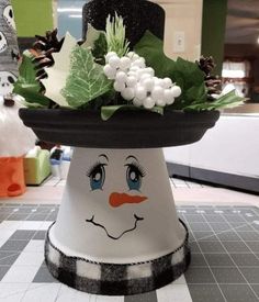 there is a snowman hat on top of the table with holly and white flowers