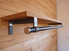 a wooden wall with some metal pipes attached to the wood paneling and two shelves on each side