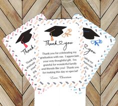 two thank you cards with graduation caps and ribbons on them, sitting on top of a wooden floor