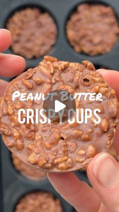 a person holding up a chocolate donut with nuts on it and the words peanut butter crisp cups in front of them