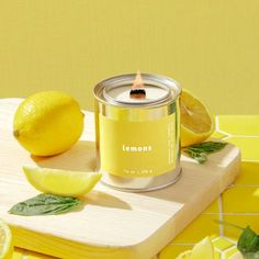 a yellow candle with lemons on a cutting board