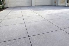 an empty driveway with two garage doors in the background