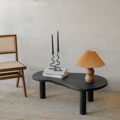 a table with two chairs and a lamp on it in front of a white wall