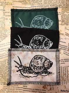 three patches with words on them sitting on top of a piece of paper that says home is wherever