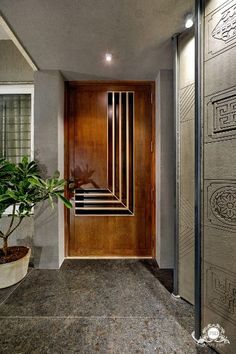 an entry way with a potted plant in the middle and a wooden door on the other side