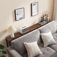 a living room with couches, lamps and pictures on the wall above them in front of a window