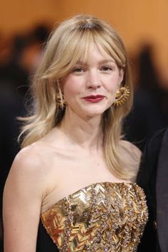 a woman in a strapless dress with large gold earrings on her head and red lips