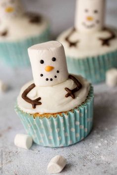 some cupcakes with frosting on them are decorated to look like snowmen