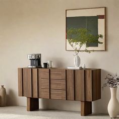 a wooden sideboard with drawers and vases on it in front of a painting