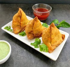 some food is on a white plate with green garnish and dipping sauces