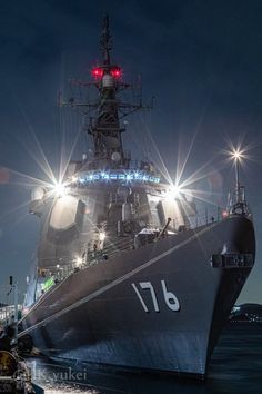 a large ship in the water with lights on it's side and some people standing next to it