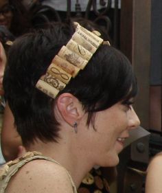 a woman with short black hair wearing a headband made out of wine corks