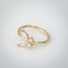 a gold ring with two small white stones on the front and one large diamond in the middle