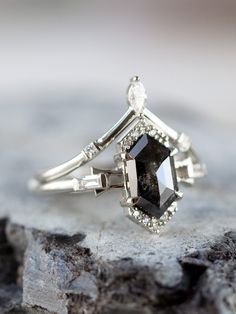 a black and white diamond ring sitting on top of a rock