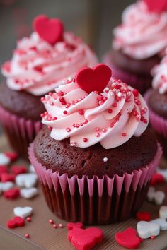 cupcakes with white frosting and red sprinkles on a table