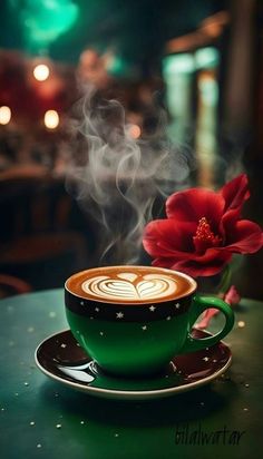 a cup of coffee on a saucer with steam rising out of it and a red flower in the foreground