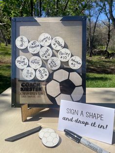 a table topped with lots of magnets next to a sign that says, sign a shape and drop it in