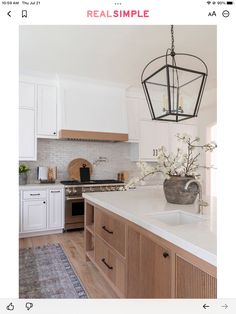 a large kitchen with white cabinets and wood accents on the countertops, along with a chandelier hanging from the ceiling