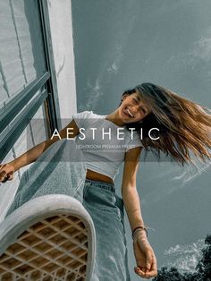 a woman standing next to a window with her hair blowing in the wind