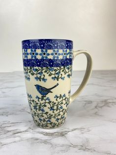 a blue and white coffee cup sitting on top of a marble countertop next to a wall