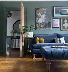 a living room with blue couches and pictures on the wall above them, along with wooden flooring