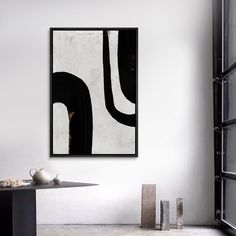 an abstract black and white painting hangs on the wall above a table with two vases