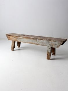 an old wooden bench sitting on top of a white floor in front of a wall