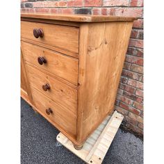 a wooden dresser sitting on top of a pallet in front of a brick wall