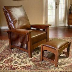 a brown leather chair and footstool sitting on top of a rug